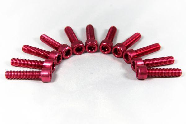 Several red anodized hexagon screws on white background