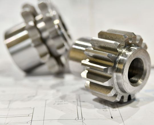 A cogwheel made on a gear cutting machine lies on the technical drawings