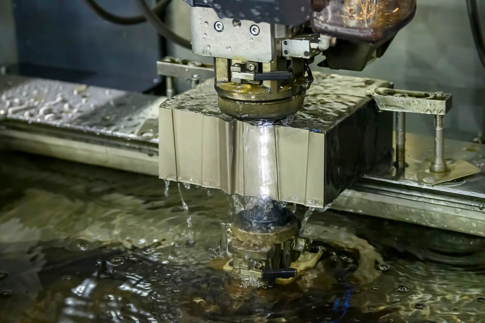 The  Wire EDM machine cutting the die parts with liquid coolant — Photo